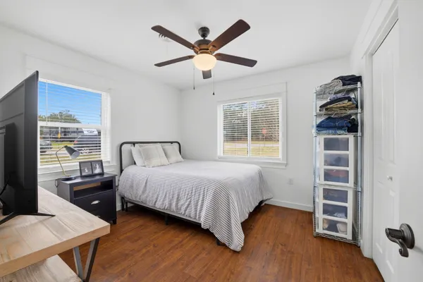 a bedroom with a bed and a desk with wooden floor