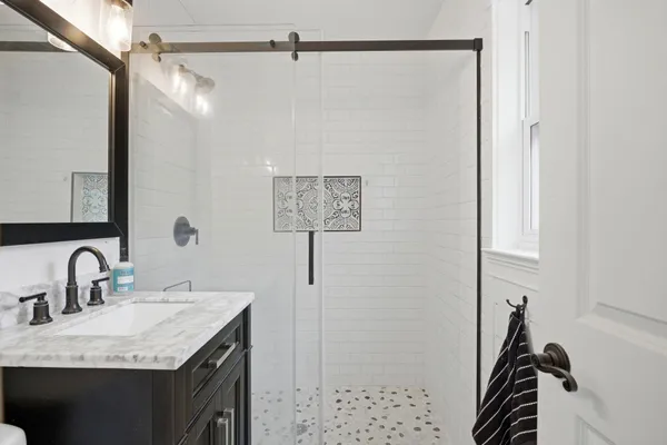 a bathroom with a granite countertop sink a mirror and shower