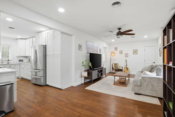 a living room with furniture a flat screen tv and kitchen view