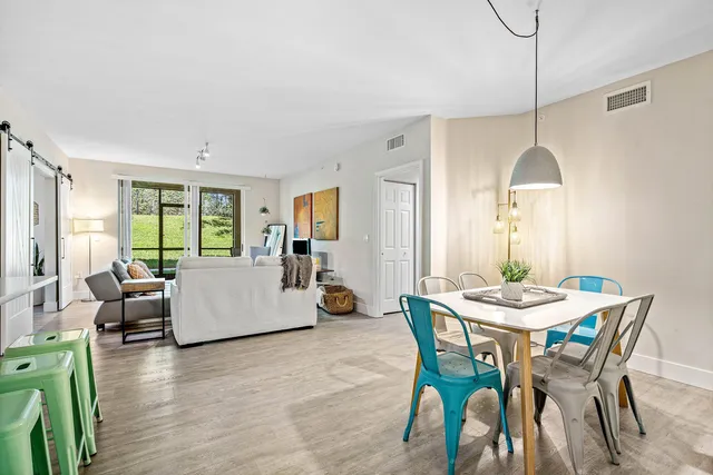 a living room with furniture large windows and wooden floor