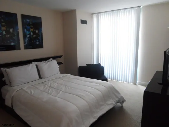 a bedroom with a bed and a flat tv screen on a dresser