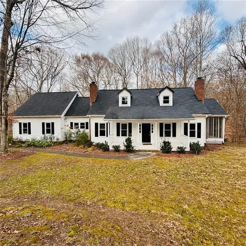 a front view of a house with a large tree
