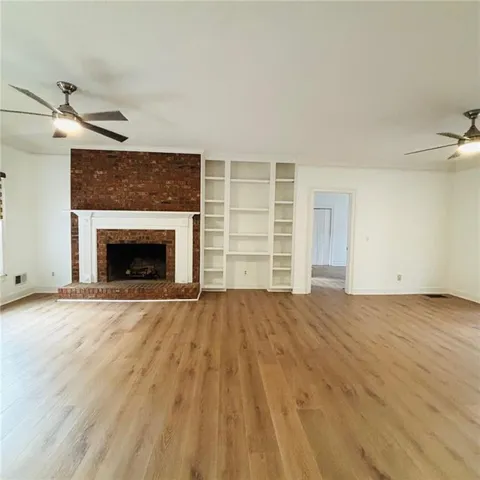 an empty room with wooden floor fireplace and windows