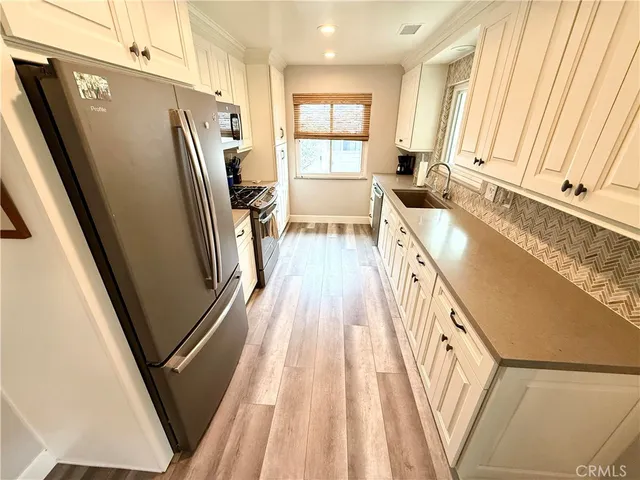 a view of a kitchen with wooden floor and electronic appliances
