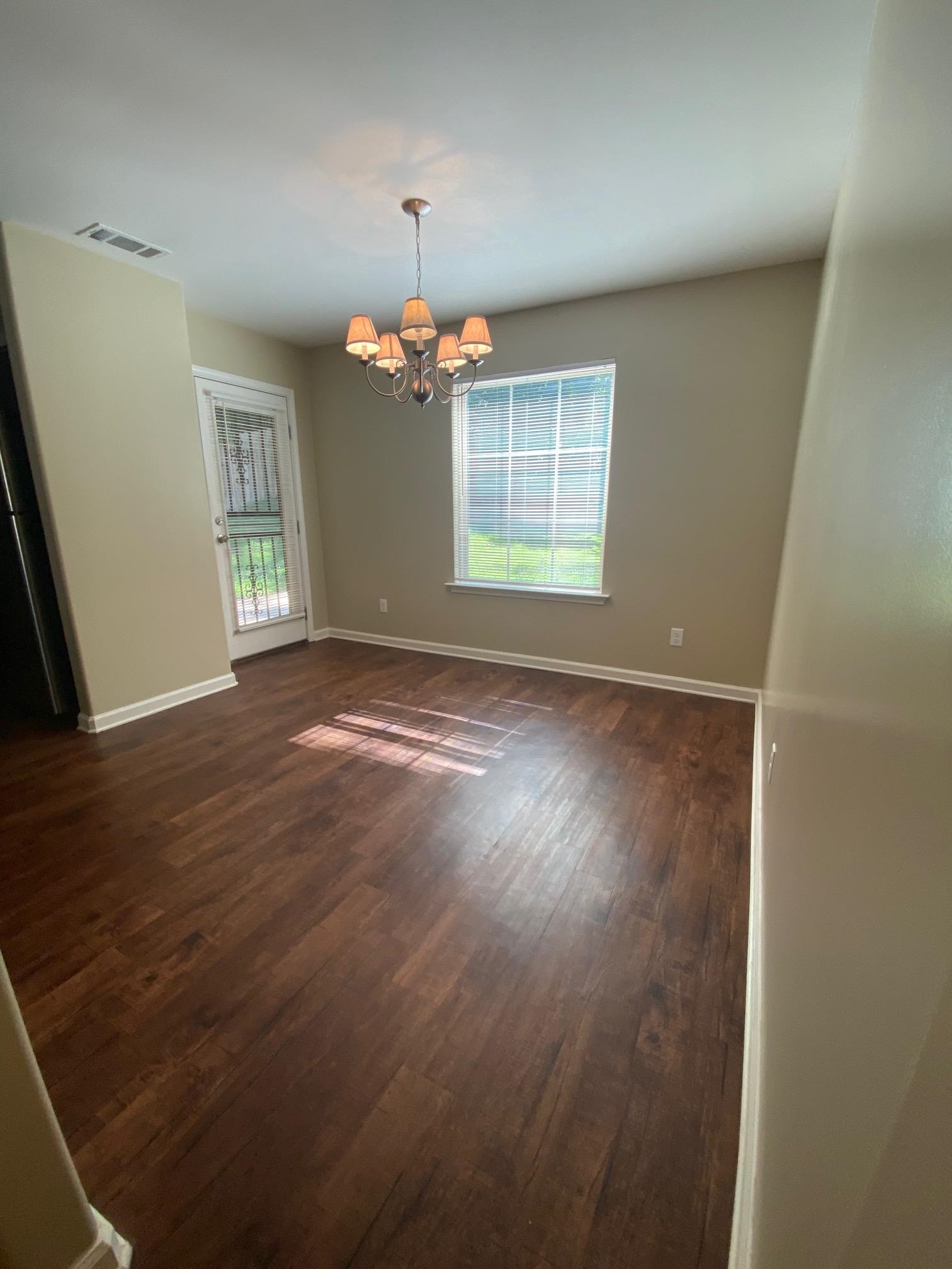 2260 Webbing Drive Memphis, TN 38016 - Photo 7 of 17 an empty room with wooden floor chandelier and window