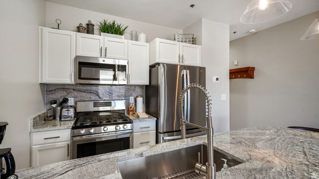 1364 Still Water Drive, Unit R2012 Heber City, UT 84032 - Photo 9 of 30 Kitchen featuring white cabinetry, stainless steel appliances, a deep stainless steel sink with a high-arc faucet, and light-toned countertops with dark veining
