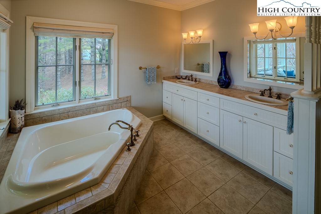 909 Daisy Ridge Road Banner Elk, NC 28604 - Photo 20 of 47 a bathroom with a granite countertop sink mirror bathtub and shower