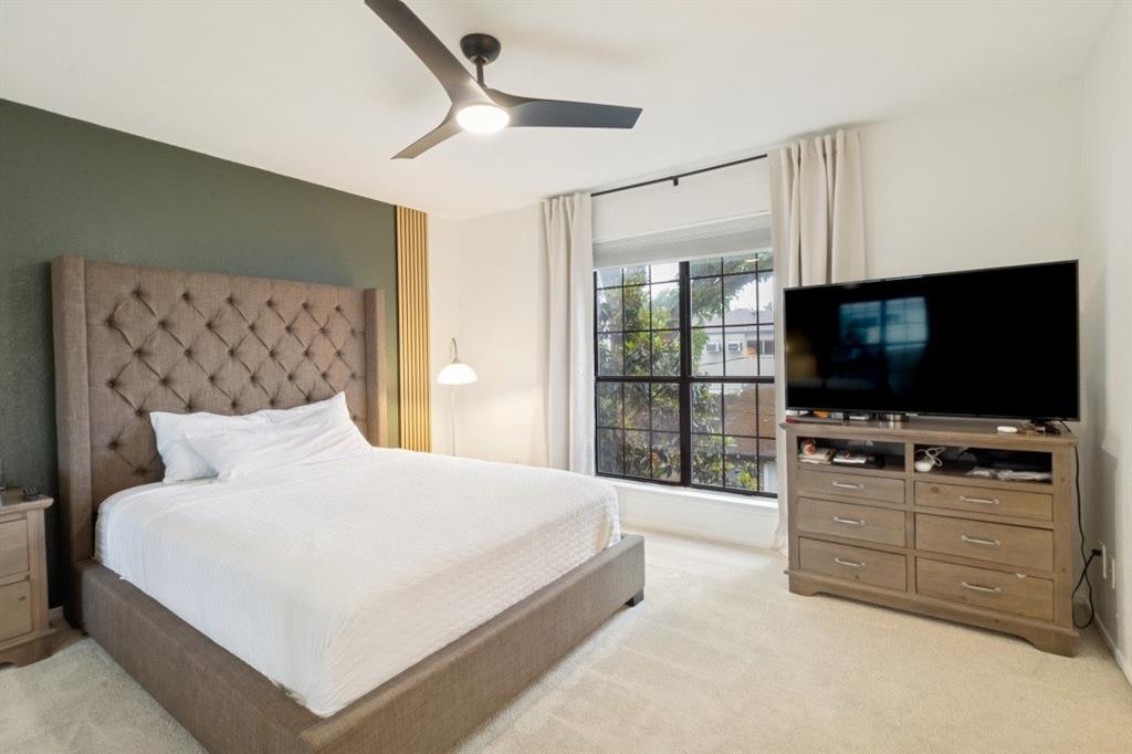 3904 Rawlins Street, Unit 112 Dallas, TX 75219 - Photo 12 of 15 Carpeted room featuring a ceiling fan with integrated lighting, a window with dark grilles, and an accent wall with vertical wood paneling