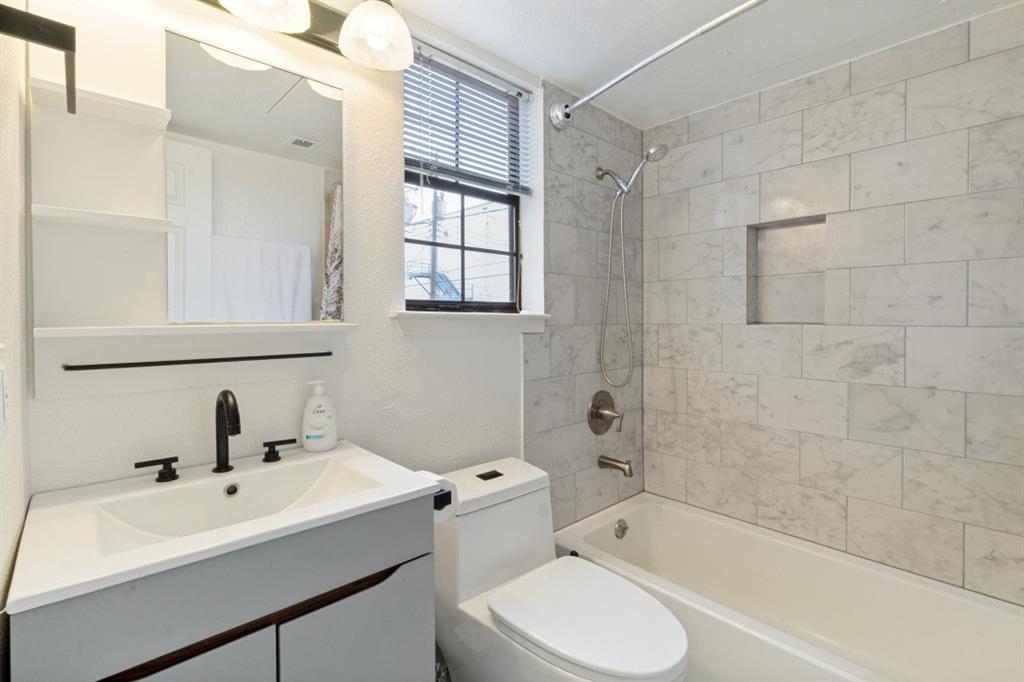 3904 Rawlins Street, Unit 112 Dallas, TX 75219 - Photo 13 of 15 Contemporary bathroom featuring a light gray vanity with an integrated sink, matte black faucet, and a large mirror