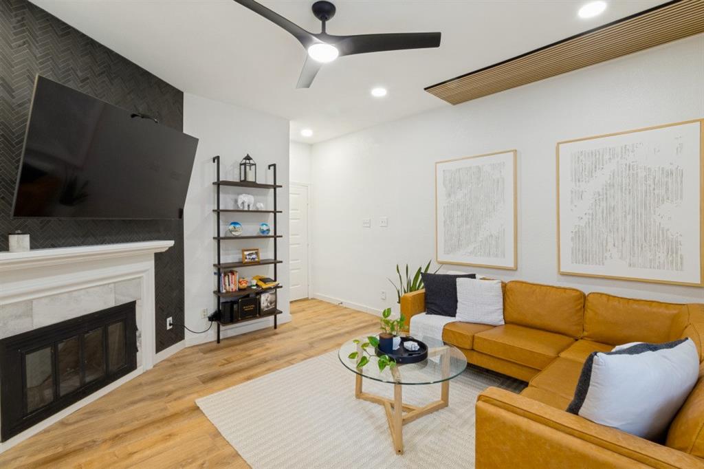 3904 Rawlins Street, Unit 112 Dallas, TX 75219 - Photo 5 of 15 Living area featuring a fireplace with a white mantel and dark tile surround, wood-finish flooring, recessed lighting, and a contemporary ceiling fan