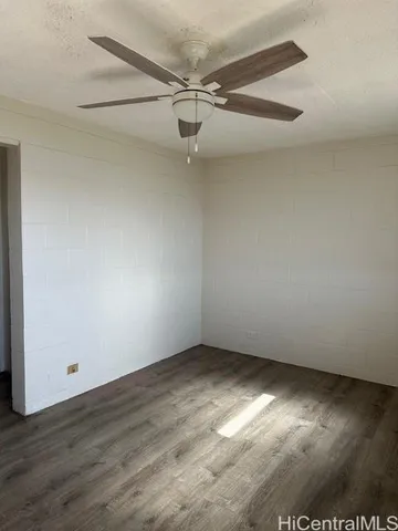 an empty room with a ceiling fan and wooden floor