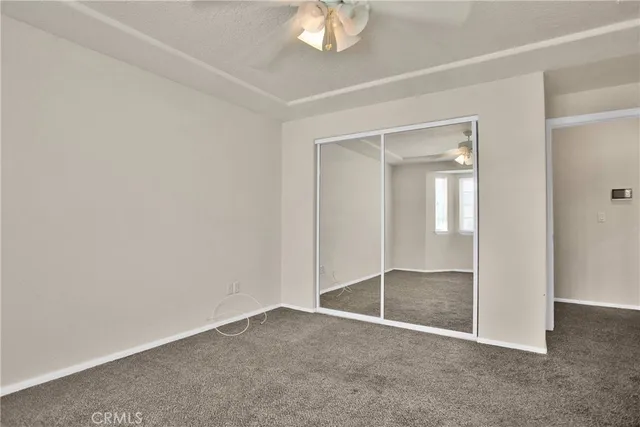 an empty room with a chandelier fan and windows