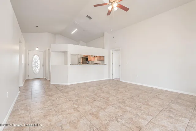 a view of a livingroom with a chandelier fan and kitchen view