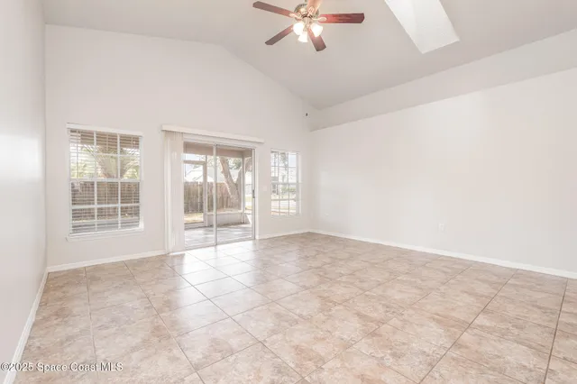 an empty room with chandelier fan and windows