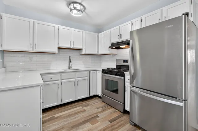 a kitchen with stainless steel appliances white cabinets and a refrigerator