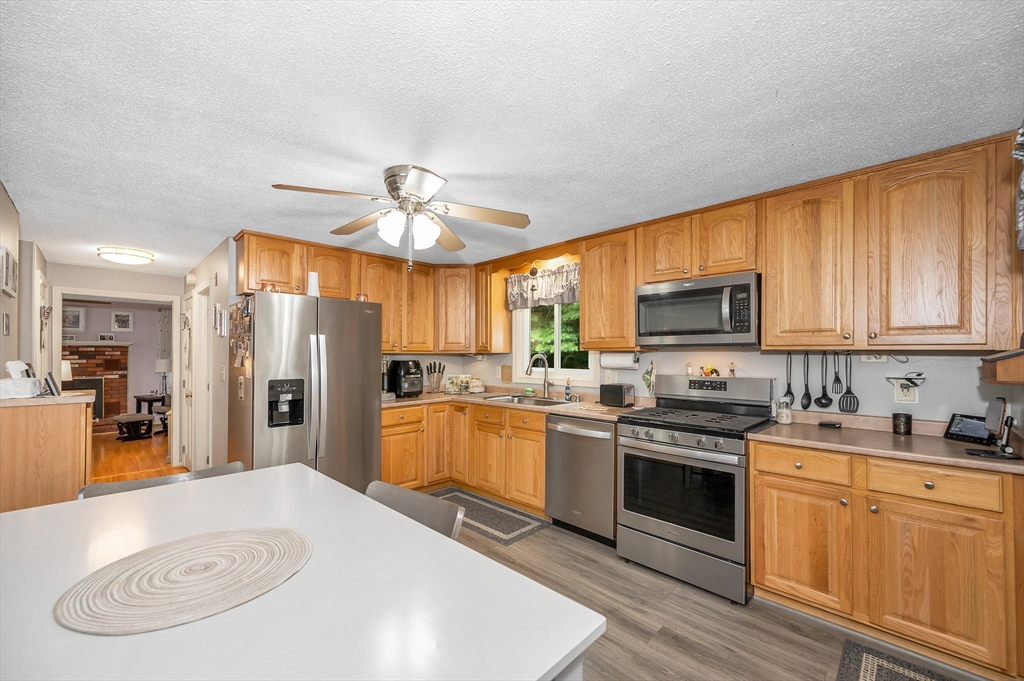 30 Partridge Road Dracut, MA 01826 - Photo 9 of 39 a kitchen with stainless steel appliances a stove a sink dishwasher a refrigerator and white cabinets with wooden floor