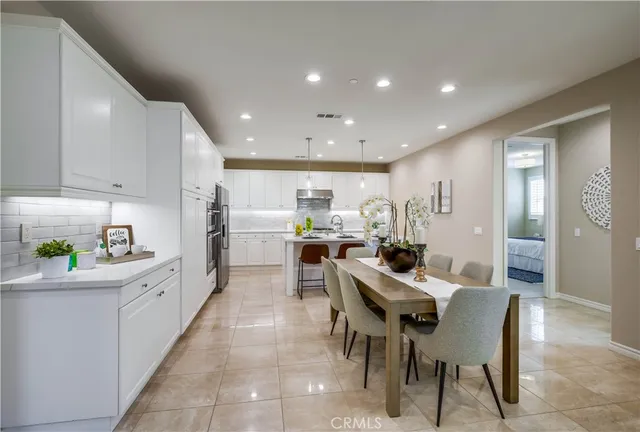 a kitchen with stainless steel appliances kitchen island granite countertop a dining table and chairs with wooden floor