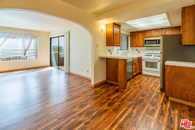 an empty room with wooden floor fireplace and windows