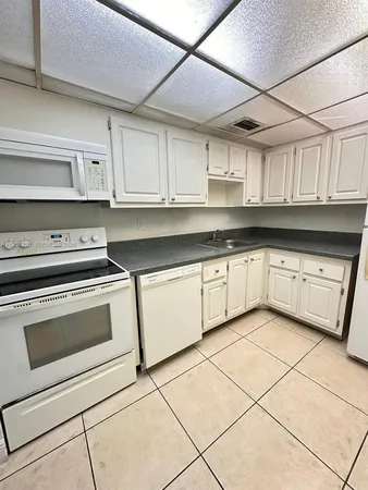 a kitchen with granite countertop a sink stainless steel appliances and white cabinets