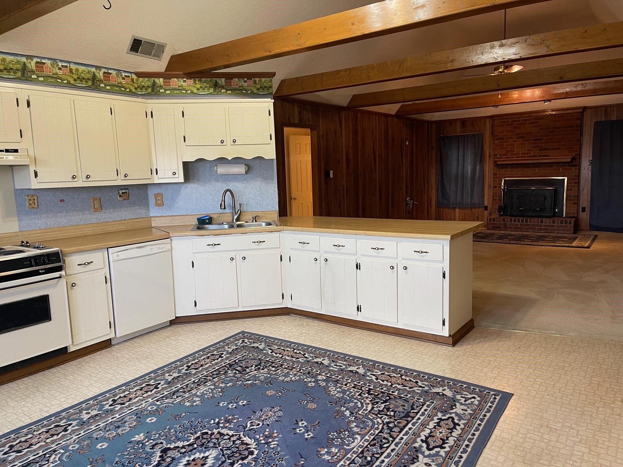 1199 McQuiston Road Brighton, TN 38011 - Photo 6 of 16 Kitchen featuring kitchen peninsula, white appliances, wooden walls, sink, and beamed ceiling