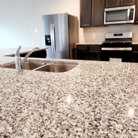 a kitchen with granite countertop white cabinets and stainless steel appliances
