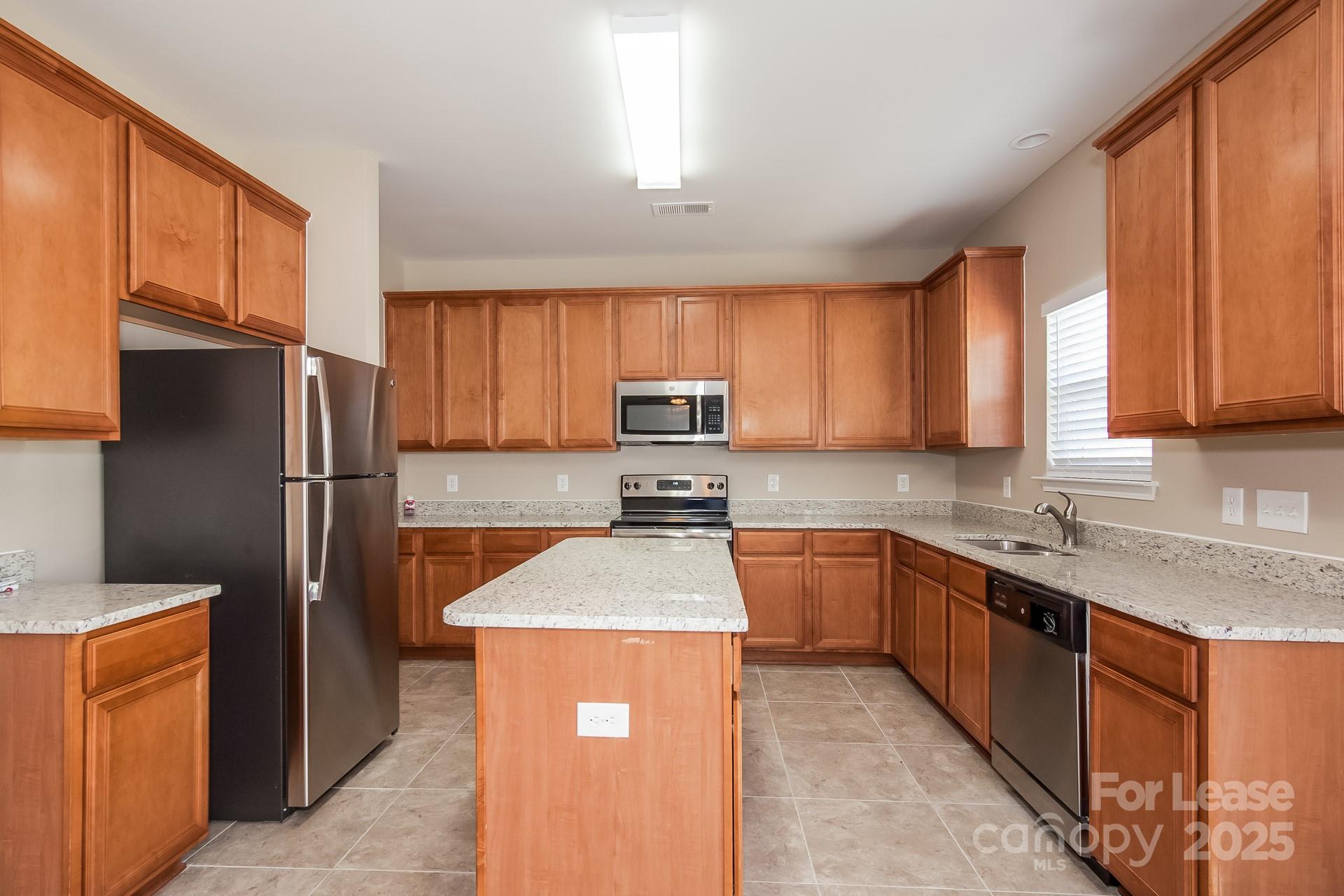 11528 Sidney Crest Avenue Charlotte, NC 28213 - Photo 5 of 15 a kitchen with granite countertop stainless steel appliances a refrigerator stove top oven and sink