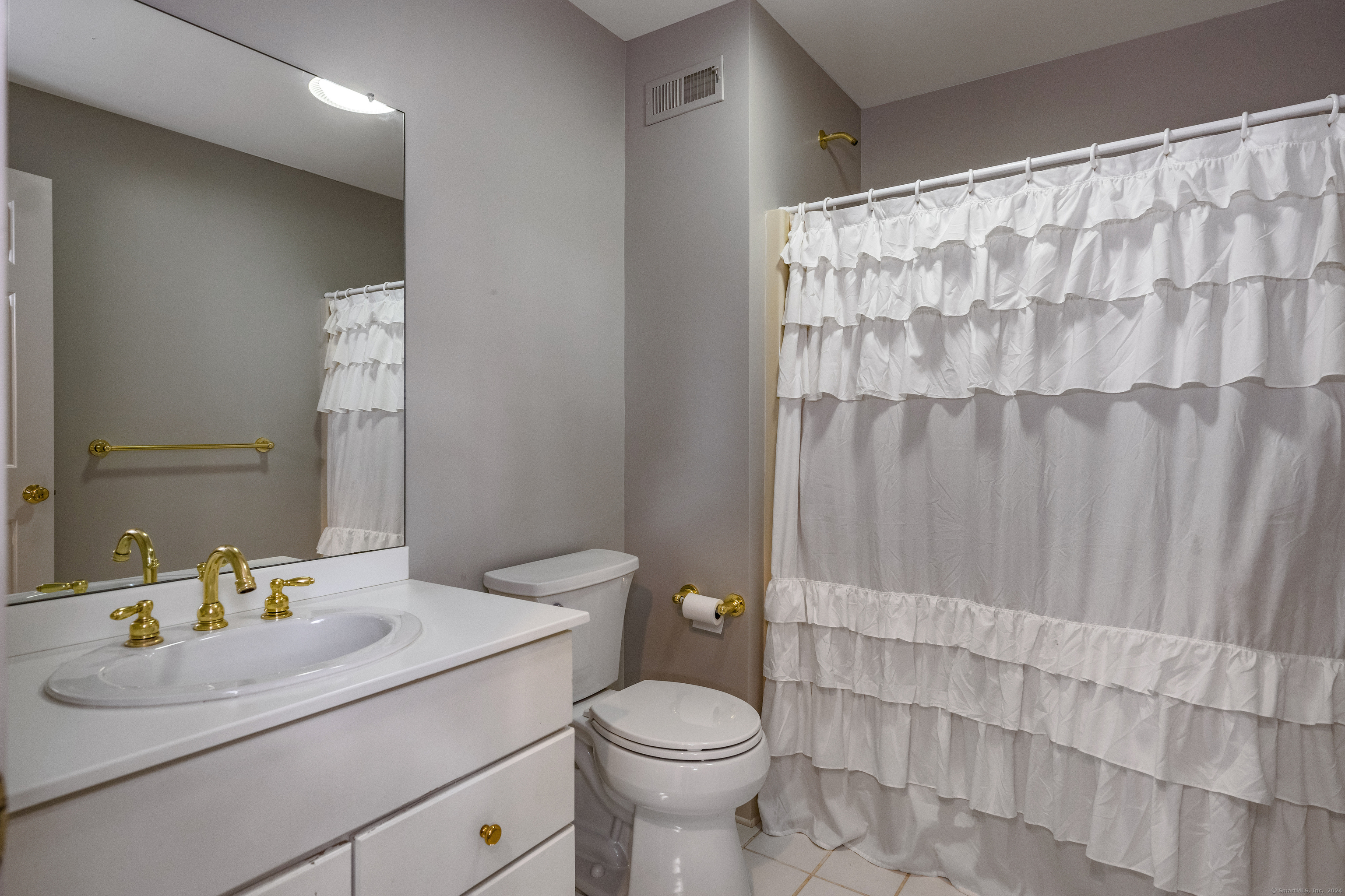 13 Longview Terrace, Unit 13 Madison, CT 06443 - Photo 19 of 31 a bathroom with a sink a toilet and shower curtain