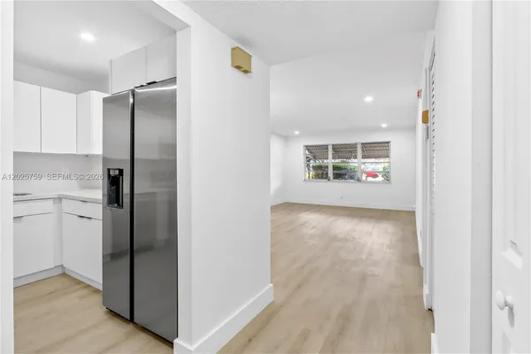 a view of a kitchen with refrigerator and wooden floor