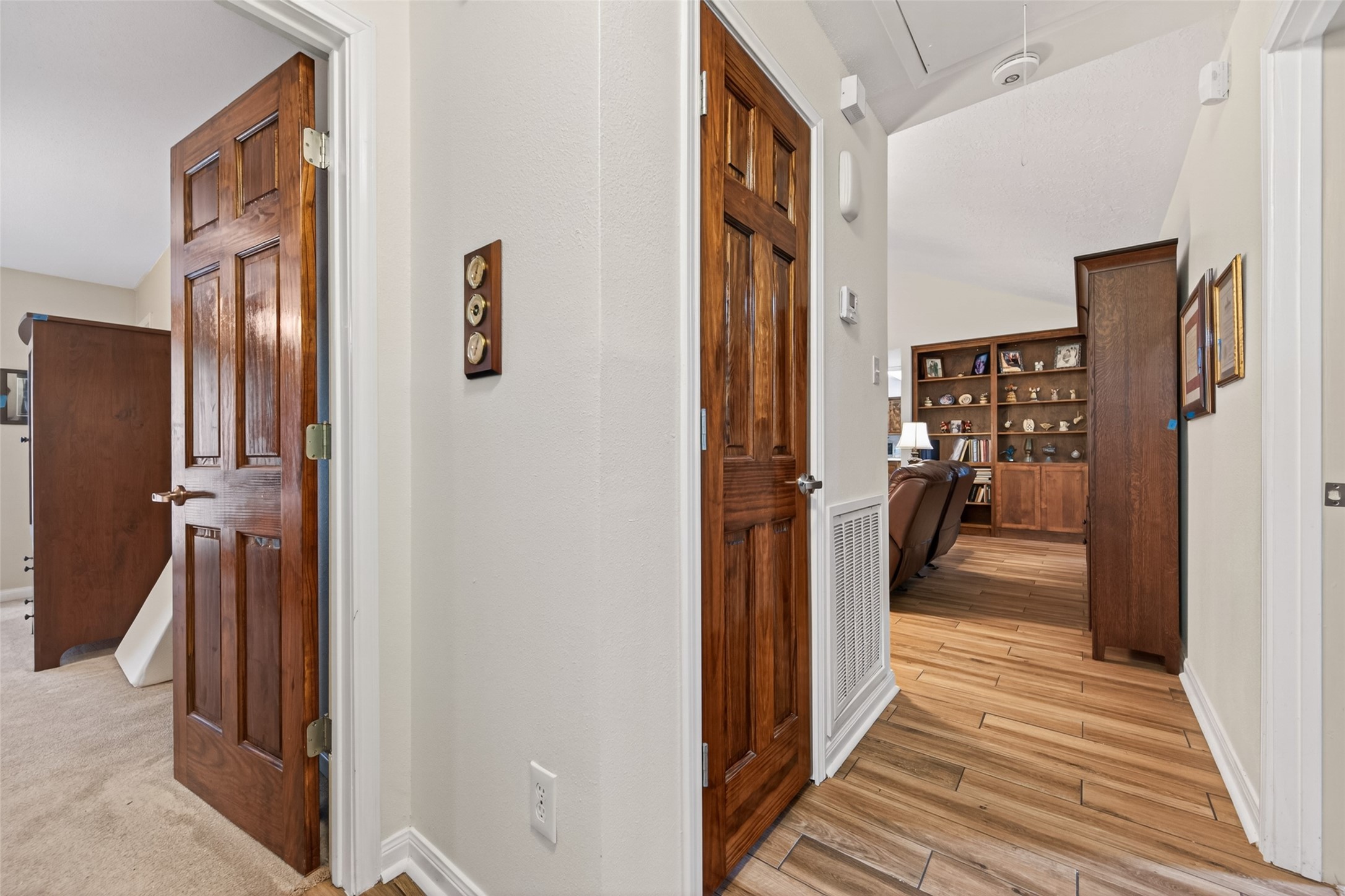 1004 Wagon Road Simonton, TX 77485 - Photo 16 of 40 This well-appointed hallway connects the home's bedrooms with beautiful rich wood panel doors that add warmth and character throughout. The wood-look tile flooring transitions seamlessly from the main living area, maintaining a cohesive and polished feel. At the end of the hall, a glimpse of the living room's built-in shelving reminds you just how thoughtfully this home flows from room to room.