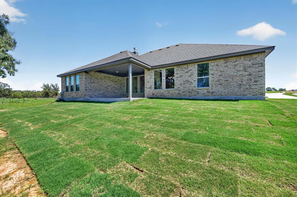 409 Mcalpine Springtown, TX 76082 - Photo 32 of 38 Expansive backyard featuring freshly laid sod and a covered patio