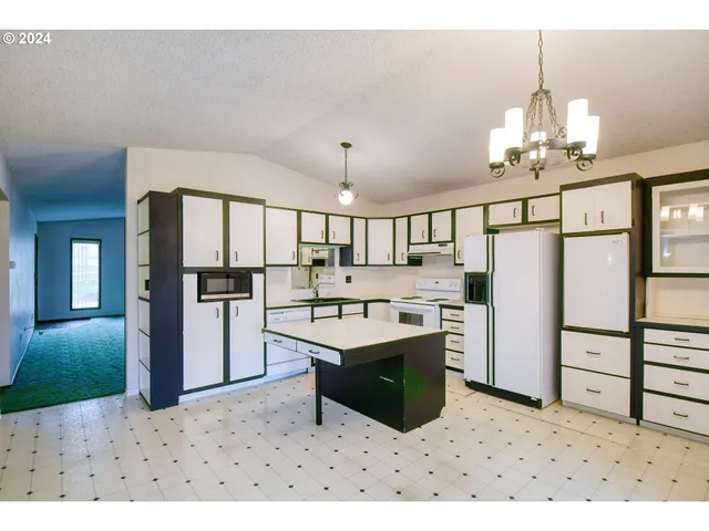 a kitchen view with appliances a sink cabinets and a window