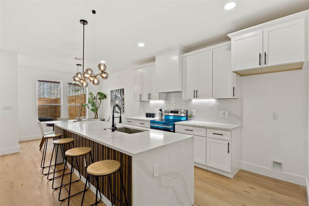 3524 Spring Avenue Dallas, TX 75210 - Photo 13 of 29 Kitchen with white cabinets, a kitchen breakfast bar, stainless steel electric range oven, and light wood-style floors