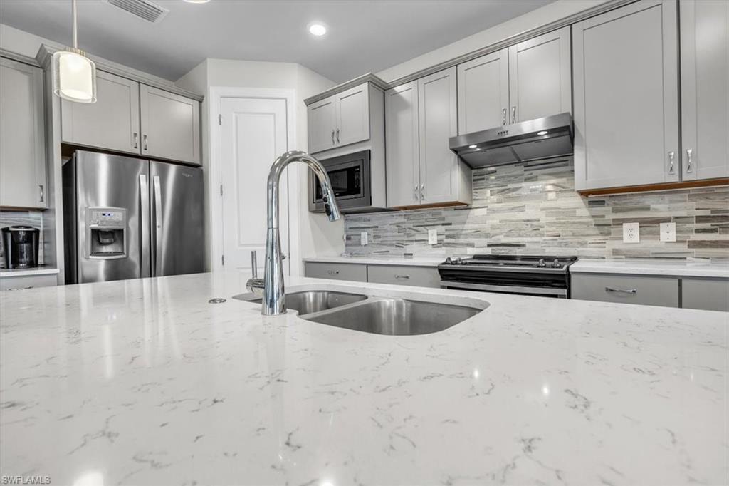 3032 Walnut Grove Lane Alva, FL 33920 - Photo 11 of 49 a kitchen with stainless steel appliances granite countertop a sink a stove and a refrigerator with cabinets