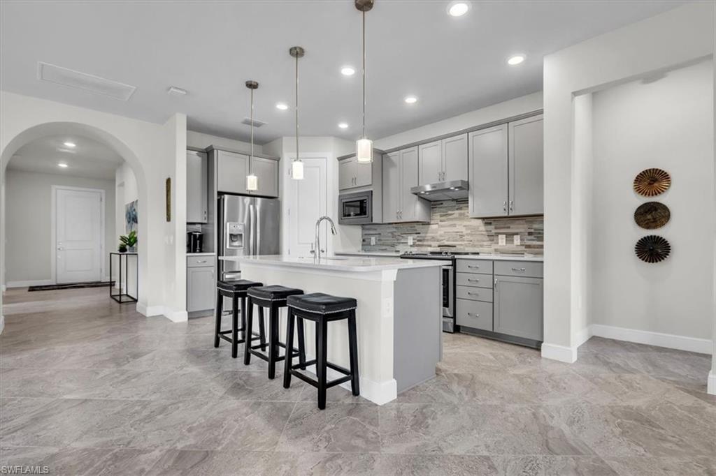3032 Walnut Grove Lane Alva, FL 33920 - Photo 9 of 49 a kitchen with stainless steel appliances kitchen island granite countertop a stove a sink a refrigerator and white cabinets with wooden floor