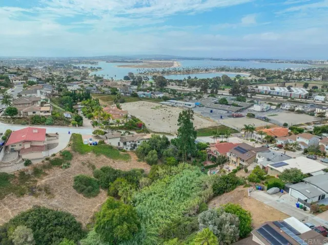 an aerial view of a city with lots of residential buildings and ocean view in back