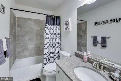 a bathroom with a granite countertop sink toilet and shower
