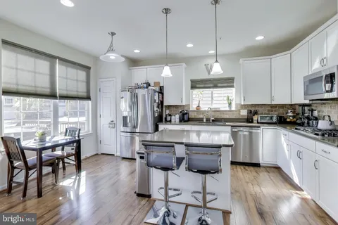 a kitchen with stainless steel appliances granite countertop a stove a refrigerator a kitchen island a dining table and chairs