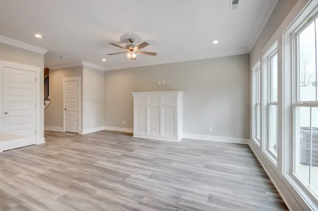 a view of an empty room with a window and wooden floor