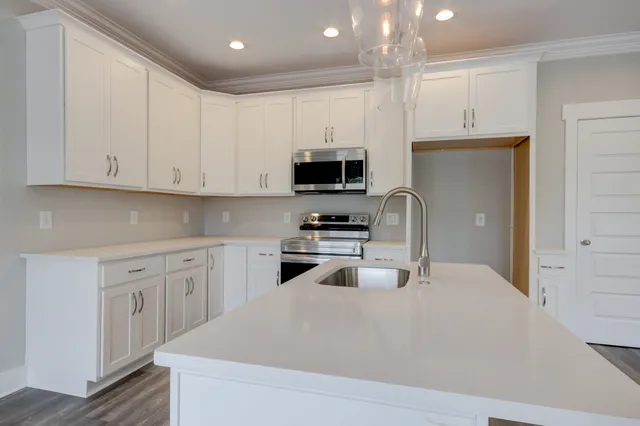 a kitchen with granite countertop white cabinets and stainless steel appliances