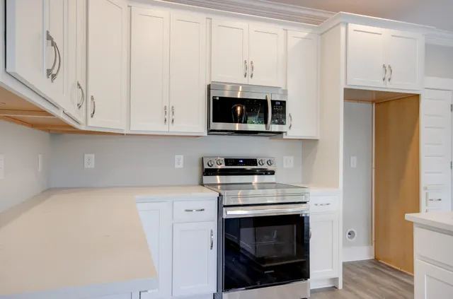 a kitchen with stainless steel appliances granite countertop a stove a microwave and a white cabinets