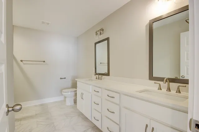 a bathroom with a granite countertop sink mirror vanity and toilet
