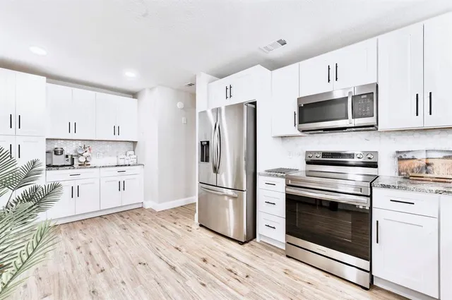 a kitchen with stainless steel appliances white cabinets a sink and a stove