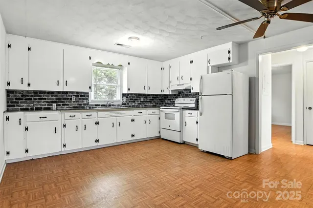 a kitchen with granite countertop a white refrigerator oven a sink and white cabinets