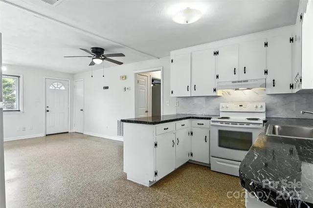 a kitchen with granite countertop a white stove top oven and white cabinets