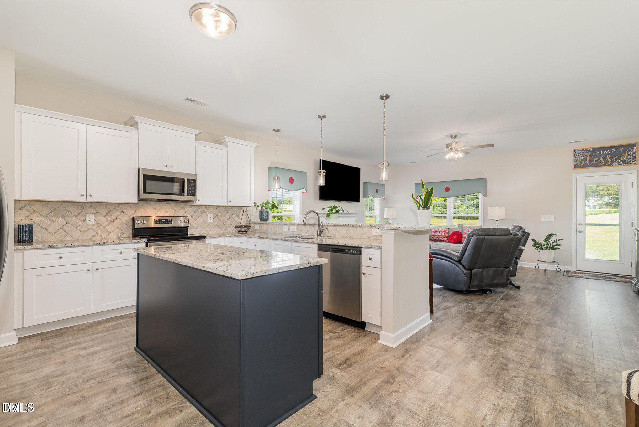 8662 Buckhorn Plantation Road Sims, NC 27880 - Photo 7 of 37 a kitchen with stainless steel appliances kitchen island granite countertop a stove top oven a sink a dining table and chairs with wooden floor