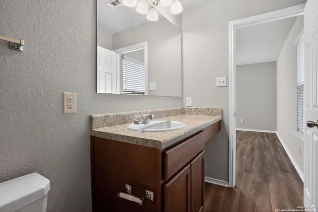 a bathroom with a granite countertop sink and a toilet