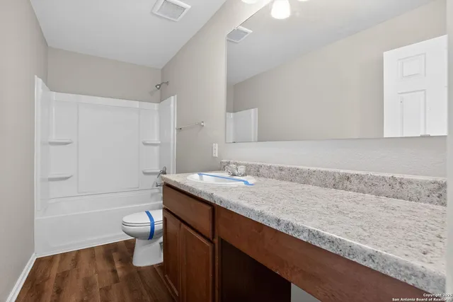 a bathroom with a granite countertop sink a toilet and bathtub
