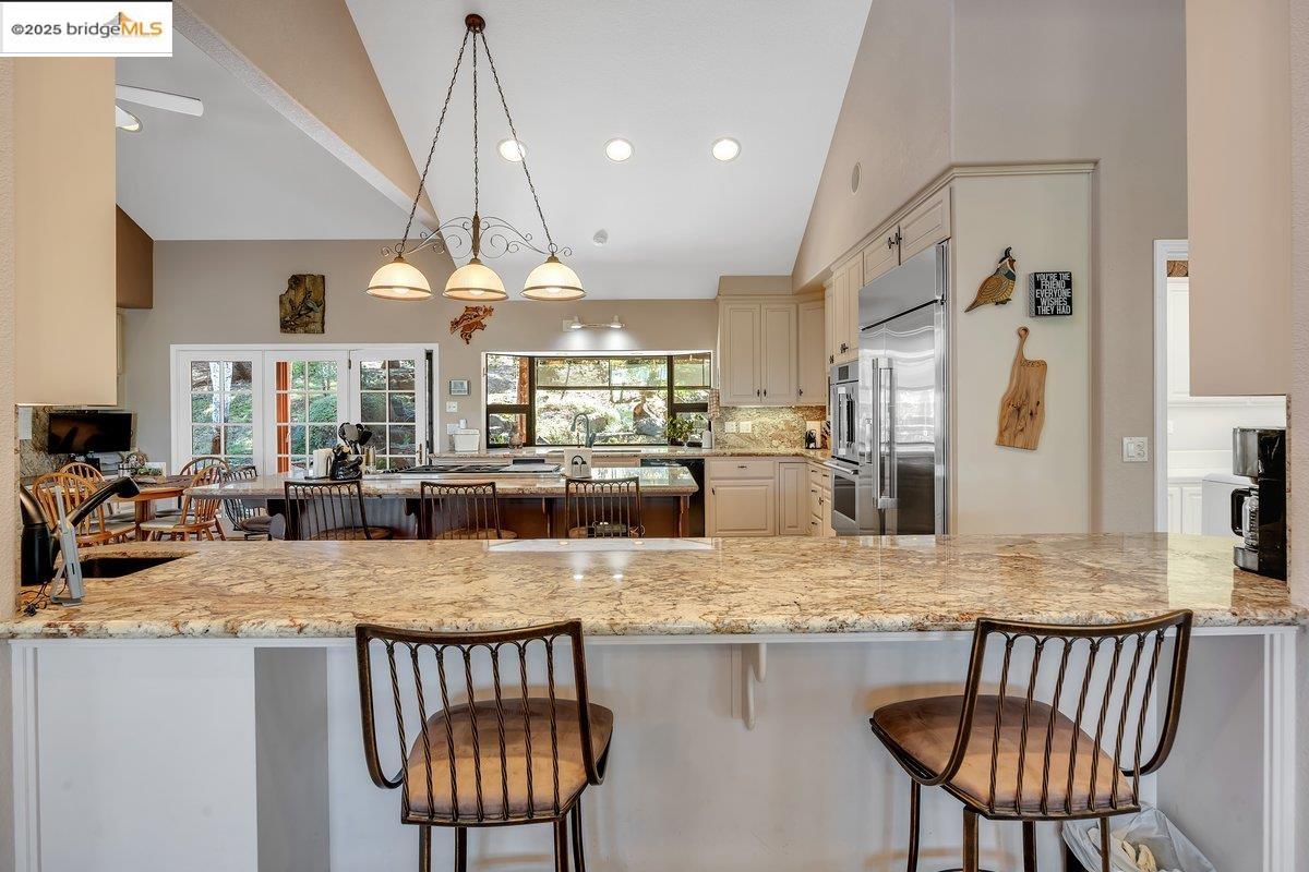 13700 Clements Road Groveland, CA 95321 - Photo 10 of 58 Kitchen with light stone countertops, a kitchen island, decorative light fixtures, tasteful backsplash, and cream cabinetry