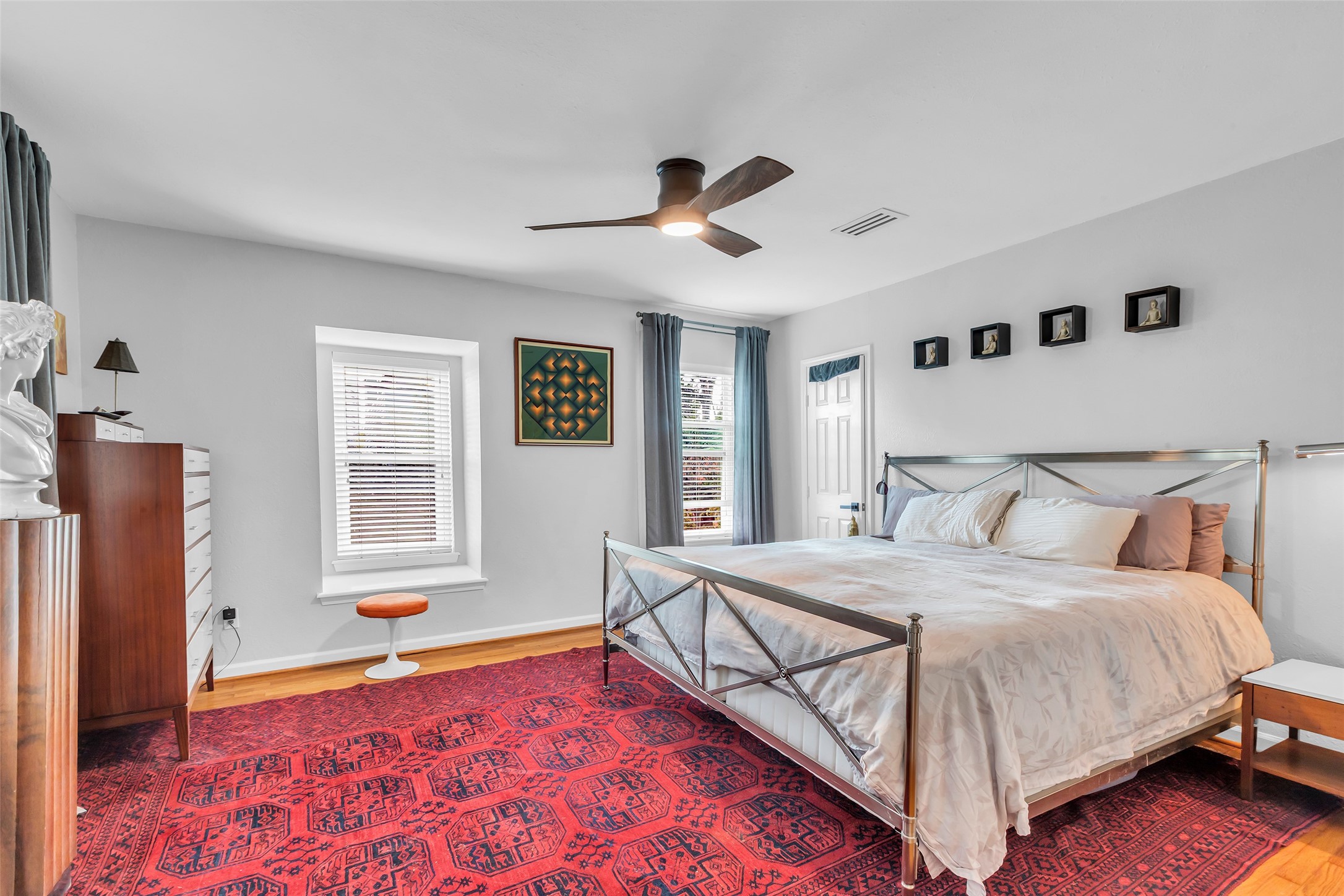 1831 Palm Street Houston, TX 77004 - Photo 21 of 26 The primary bedroom features oak wood flooring and windows facing the front, filling the space with natural light. A corner door provides access to a spacious walk-in closet, adding convenience and storage.