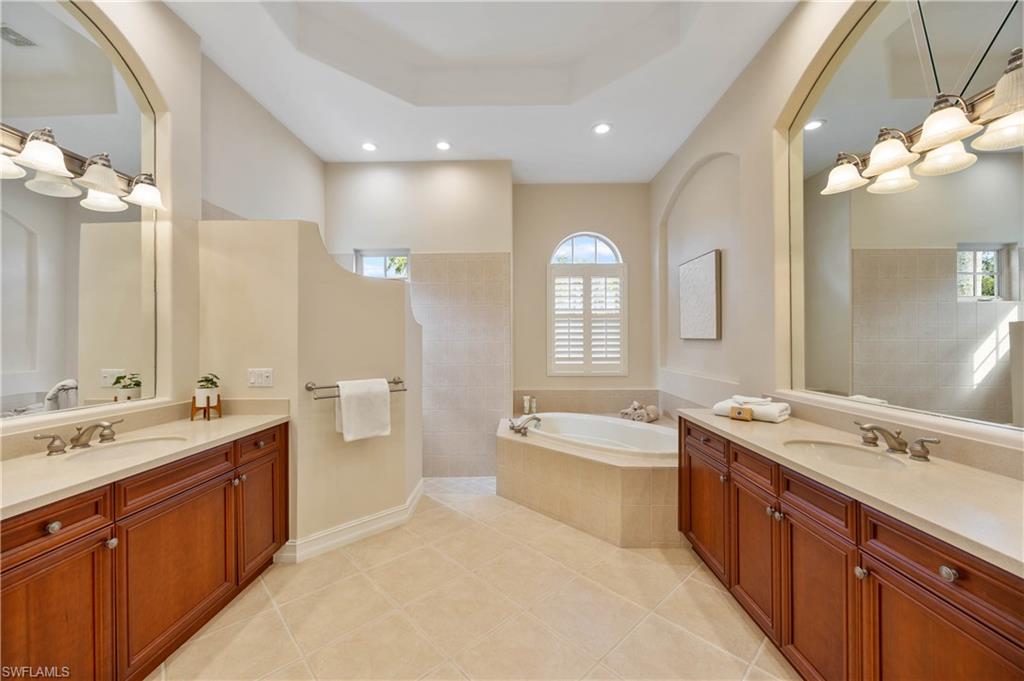 8950 Shenendoah Circle Naples, FL 34113 - Photo 16 of 48 a spacious bathroom with a double vanity sink a large mirror and a bathtub